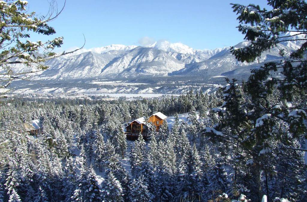 Winter image of forest, mountains, and cabin.