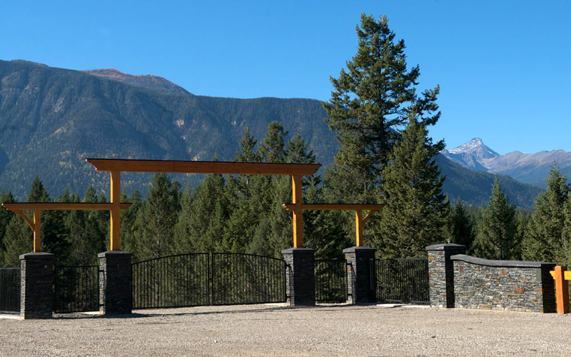 Photo of beautiful timber frame and cultured stone front gate with mountains in the background.