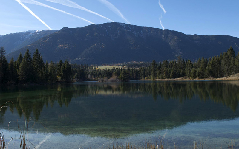 Image of a mountain behind a calm lake, with reflection of mountain in the lake.