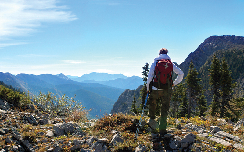 Image of back packer taking in the view from the mountain top.